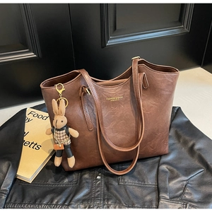 Détail d'un grand sac cabas vintage marron avec logo doré et pendentif lapin en peluche