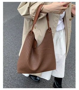 Outdoor lifestyle view of dark brown woven leather tote bag paired with beige trench coat