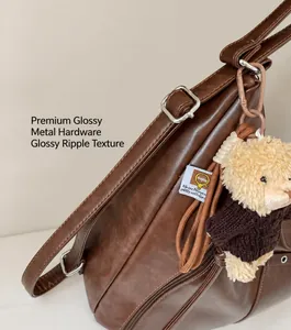 Close-up of brown PU leather backpack with silver hardware and cute teddy bear pendant
