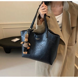 Détail du grand sac cabas noir en cuir avec logo doré et pendentif lapin sur mannequin