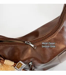 Detail of silver zipper closure and leather texture on a brown commuter backpack