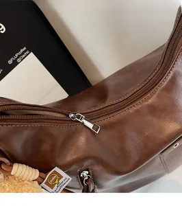 Detail of silver zipper closure and leather texture on a brown commuter backpack