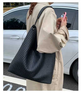 Close-up of black woven leather tote bag with minimalist strap and matte texture detail