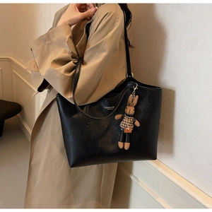 Détail d'un grand sac cabas en similicuir noir avec breloque lapin et texte imprimé