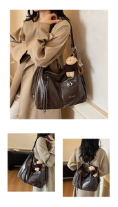 Detail view of large dark brown tote bag with premium leather texture and bear charm