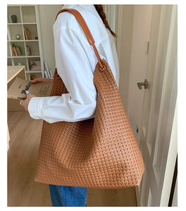 Detailed view of brown woven tote bag showing premium PU leather texture and shoulder strap