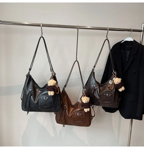 Modern Hobo bags in black and tan leather with plush bear charms on display