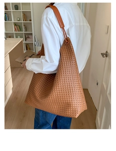 Detail of large brown woven leather tote bag showing intricate cross-weave texture
