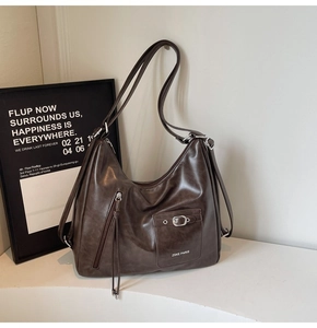 Close-up of vintage brown PU leather bag with metal buckle and fringe zipper detail
