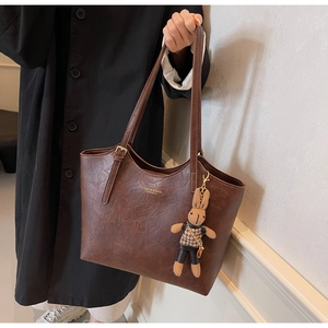 Détail du sac cabas marron vintage avec breloque lapin en peluche et logo imprimé