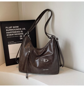 Detail of dark brown matte leather hobo bag with metal buckle pocket and tassel zipper