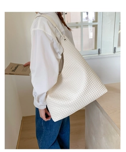 Close-up of the cream woven texture and intricate cross-weave pattern on the tote bag