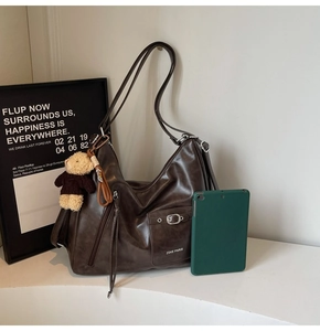 Detail of vintage brown PU leather tote bag with front pocket, buckle and bear charm
