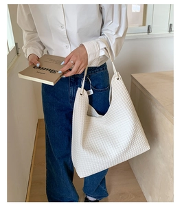 Detailed close-up of white woven texture hobo bag with minimalist shoulder strap design
