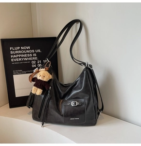 Detail of black Hobo bag featuring silver buckle pocket and cute teddy bear charm