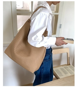 Close-up of a large woven tote bag in camel leather, styled with a modern casual outfit