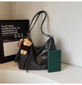 Detail view of black PU leather tote bag with pocket and brown teddy bear charm