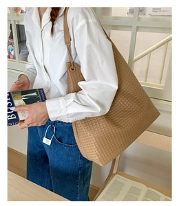 Close-up of caramel woven tote bag worn with white shirt and jeans for office look