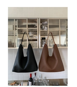 Detail view of woven leather texture on black and brown tote bags in a home setting