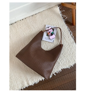 Detailed view of dark brown woven leather texture on a stylish hobo shoulder tote bag