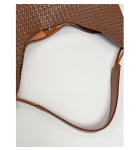 Close-up of brown woven tote bag showing fine Intrecciato texture and magnetic closure