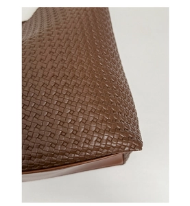 Detail shot of brown woven leather texture and fine edge oil finish on tote bag
