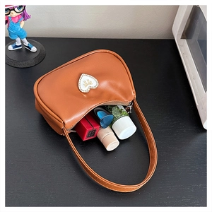 Detailed view of brown leather handbag interior with heart charm and zipper closure