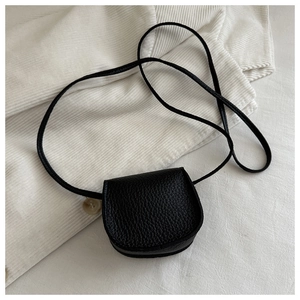 Detail of black mini heart saddle bag showing fine lychee grain leather texture and strap