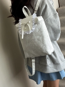 White ruffle backpack for women with floral embossing, bow detail, and pearl pendant