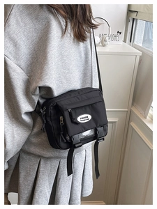 Detail of black nylon crossbody bag with double buckle flap and side zipper pocket