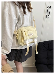 Detail view of cream nylon messenger bag with adjustable strap and mesh pocket