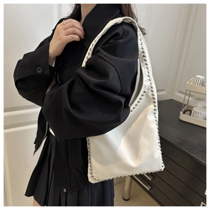 Detail view of white leather shoulder bag featuring stylish silver metal rivets along the edge