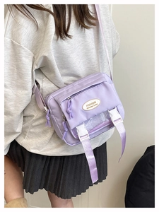Detailed side view of light purple canvas messenger bag with adjustable white buckle strap