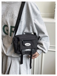 Detail of black nylon messenger bag with buckle closure and adjustable shoulder strap