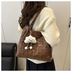 Detail of brown tote bag with bear embossing and cloud plush pendant accessory