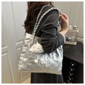 Detail of silver metallic tote bag featuring bear embossing and a plush cloud charm