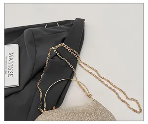 Close-up of golden textured handbag featuring metallic chain strap and circular metal handle