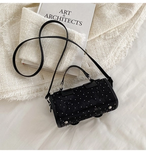 Detailansicht einer schwarzen Zylindertasche mit weißen Punkten und Bodennieten zum Schutz