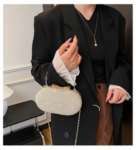 Detail of champagne gold evening clutch featuring glitter texture and bow clasp