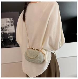 Détail de pochette de soirée avec fermoir nœud doré, texture melon et chaîne métal