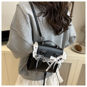 Detail of sweet Lolita black leather crossbody bag with lace edges and bow accents