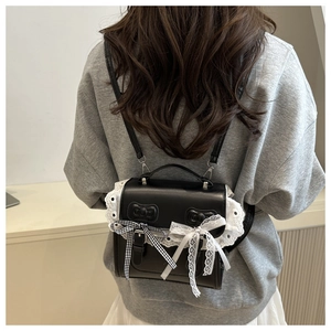 Detail view of mini black leather backpack with white lace trim and bowknot details