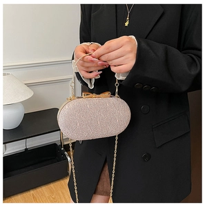 Détail de la pochette rose texture melon avec nœud doré et bandoulière chaîne