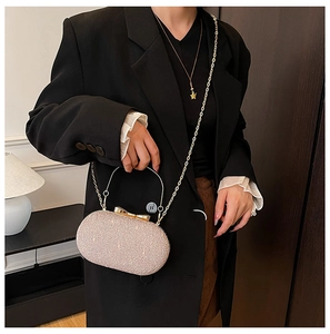 Pochette de soirée pailletée rose champagne avec fermoir nœud doré portée par un modèle