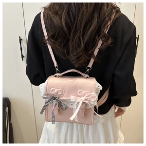 Detail of pink faux leather mini backpack featuring white lace edges and bow accents