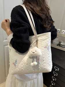 White tote bag with colorful butterfly embroidery and a plush cloud charm on a shoulder strap