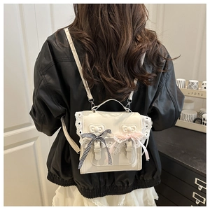 Detail of white PU leather Lolita backpack with lace trim and decorative bows on model