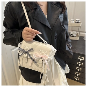 Close-up of creamy white lace handbag featuring decorative bows and PU leather texture