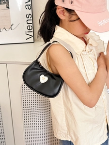 Elegant black crescent shoulder bag with pearl heart detail on female child model