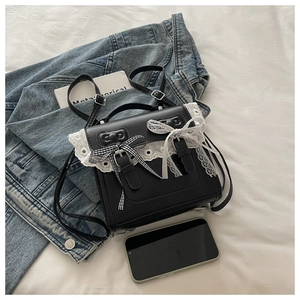 Close-up of black PU leather bag featuring white lace trim and bow knot details